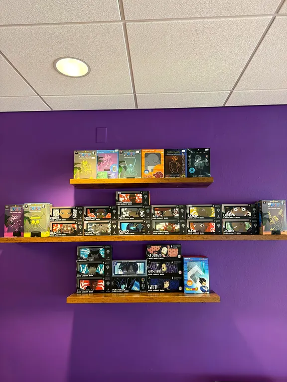 Purple wall of black shelves holding One Piece boxes, Funko Pops, and plush